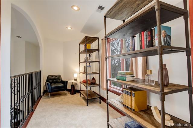 Upstairs reading nook with open bookshelves, a black leather chair, and large windows.