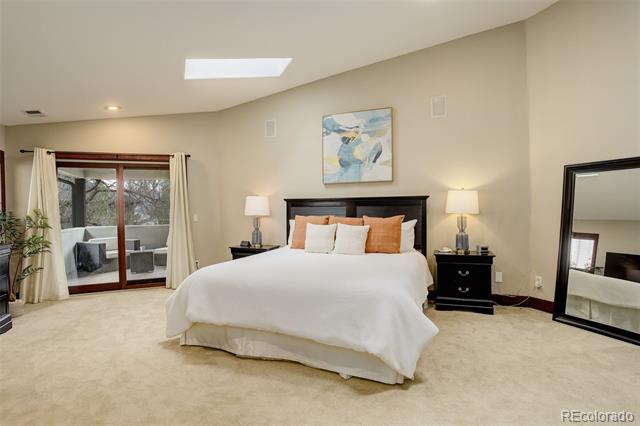 Staged bedroom with a white bed, dark wood furniture, and sliding glass doors opening to a patio.