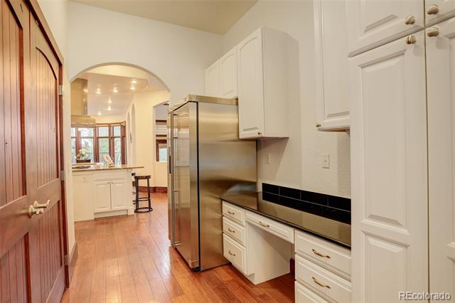 Kitchen with white cabinets, stainless steel appliances, and an arched opening to a bright dining area.