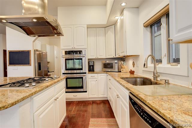 Kitchen with white cabinets, granite counters, stainless steel appliances, and a sink beneath a window.
