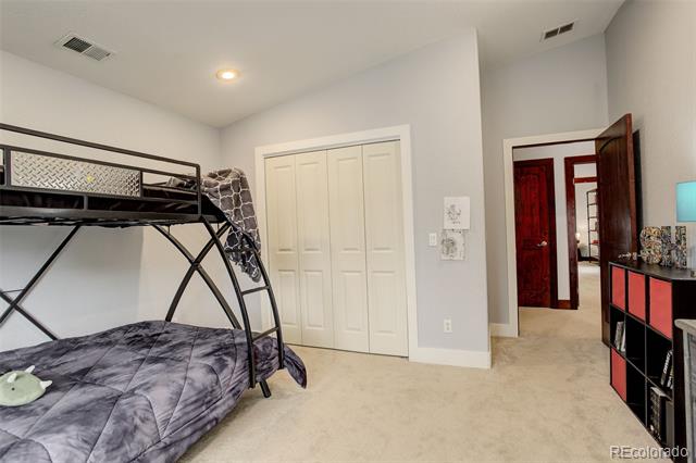 Bedroom with a black metal bunk bed, gray patterned bedding, and white closet doors.