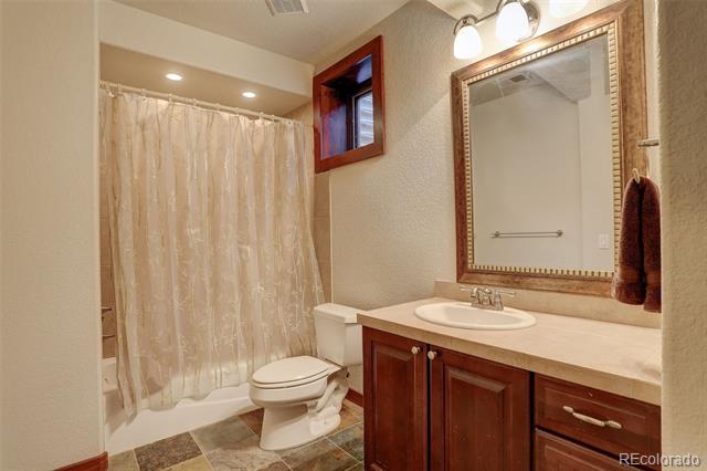 Bathroom with a curtained tub and shower, toilet, and dark wood vanity.