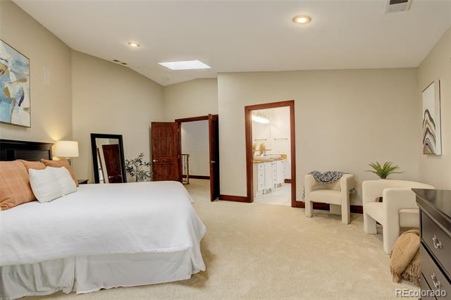 Bedroom with a large white bed, seating area, and doorway to a bathroom.