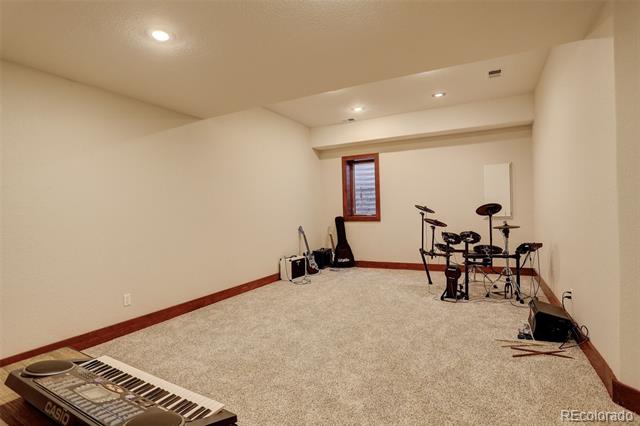 Carpeted basement music room with an electronic drum kit, guitar, and keyboard.