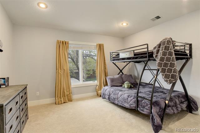Bedroom with a gray daybed, black metal loft bunk, and gold curtains framing the window.