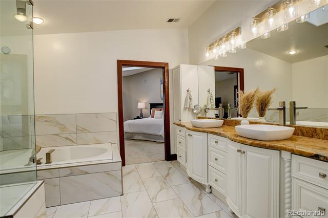 Bathroom with a soaking tub, glass shower, and double vanity with vessel sinks.