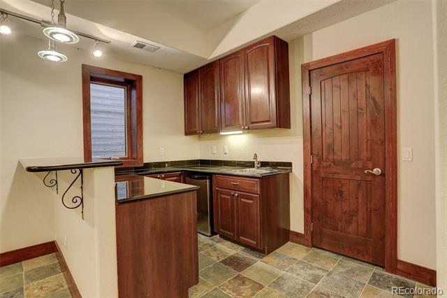 Compact kitchen with dark wood cabinets, tiled floor, and a narrow counter on decorative metal brackets.