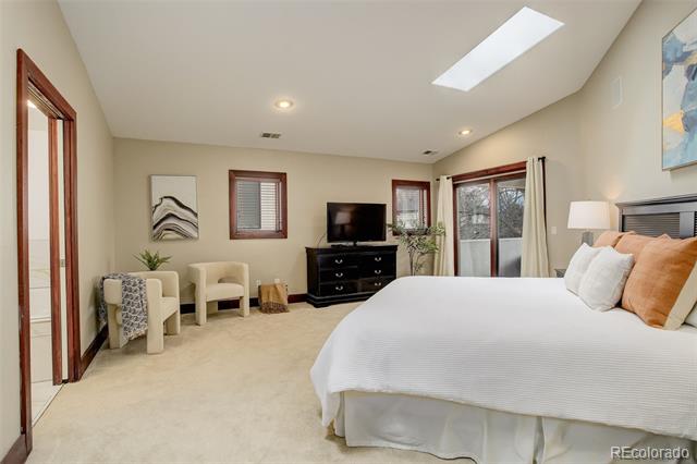 Spacious bedroom with a large bed, sitting area, television, and sliding glass doors.