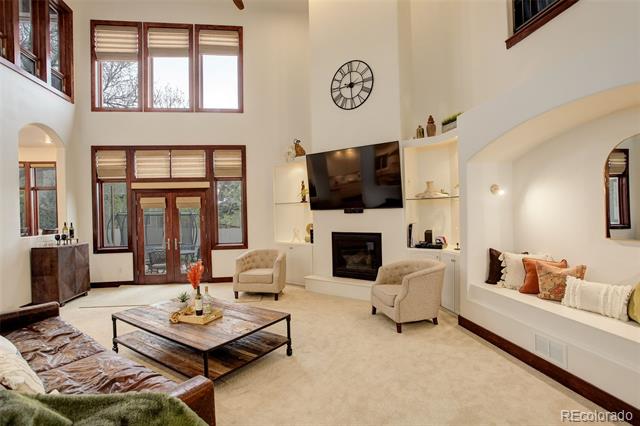 Living room with tall windows, a fireplace, built-in shelving, and a cushioned window seat.