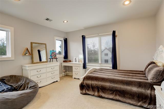 Bedroom with a brown-covered bed, white dresser, and windows framed by dark blue curtains.