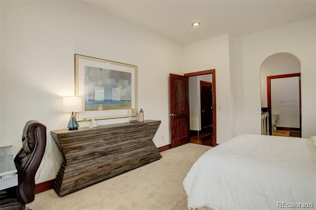 Bedroom with a white bed, rustic wood dresser, framed artwork, and an open wooden door.