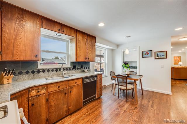 Kitchen with warm wood cabinets, granite counters, hardwood floors, and an adjoining dining table.
