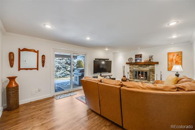 Living room with a tan leather sectional, stone fireplace, and sliding doors overlooking snow.