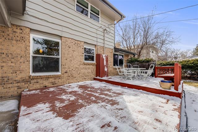 Snow-covered backyard patio with red deck edging and a white outdoor dining set.
