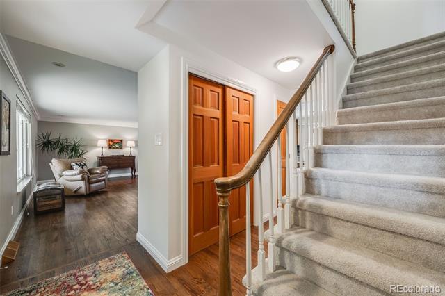 Entryway with carpeted staircase and wood doors, opening onto a furnished living room.