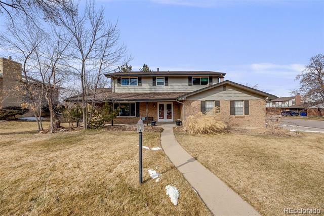 Two-story brick-and-siding home with a curved front walkway and dormant winter lawn.