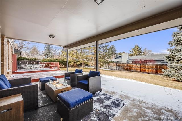Covered patio with wicker seating and a fire table overlooking a snow-dusted backyard.