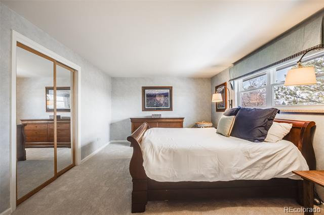 Bedroom with a dark wood bed, mirrored closet doors, and wide windows.