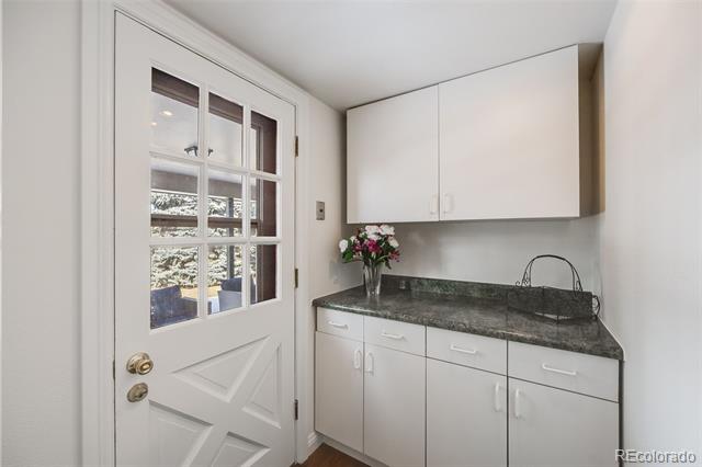 Small room with white cabinets, dark countertop, compact sink, and a glass-paneled exterior door.