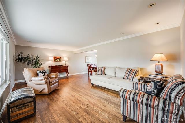 Living room with hardwood floors, a white sofa, and striped armchairs.