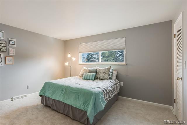 Bedroom with teal bedding, patterned pillows, and a wide window above the bed.