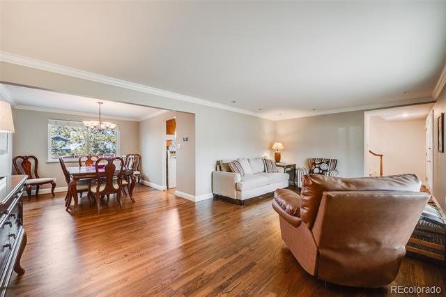 Open-plan living and dining room with hardwood floors, white sofa, and brown leather seating.