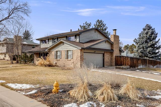 Two-story house with brick and gray siding, an attached garage, and a snow-dusted lawn.