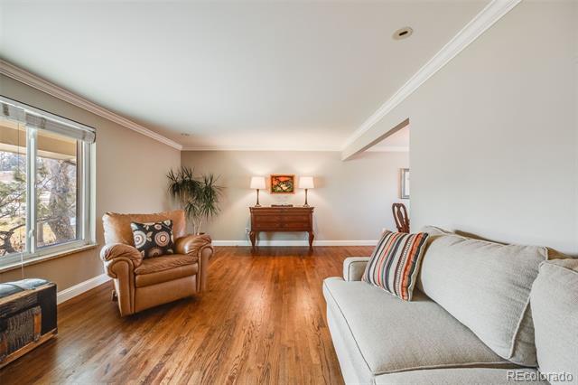 Living room with hardwood floors, a gray sofa, leather armchair, and large window.