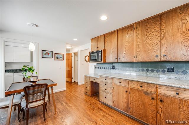 Kitchen with honey-toned wood cabinets, stone counters, patterned tile backsplash, and an adjoining dining table.