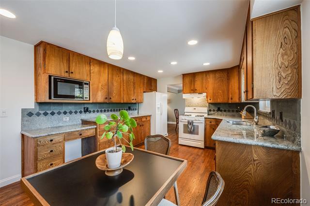 Kitchen with warm wood cabinets, granite counters, and a dark dining table with a potted plant.