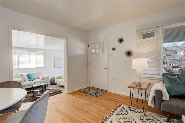 Furnished entryway with a white front door, wood floors, and a living area visible through the doorway.