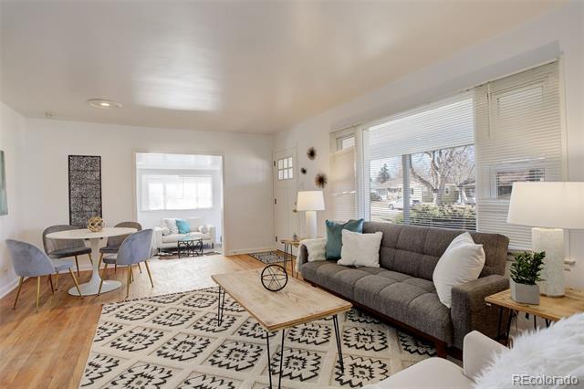 Living room with a gray sectional, large windows, patterned rug, and adjoining dining area.