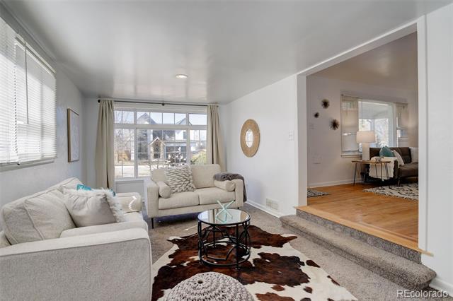 Living room with two light sofas, a glass coffee table, cowhide rug, and sliding doors to a patio.