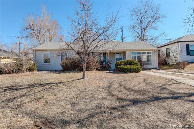 Single-story ranch house with light blue siding, covered entry, leafless front yard tree, and driveway.