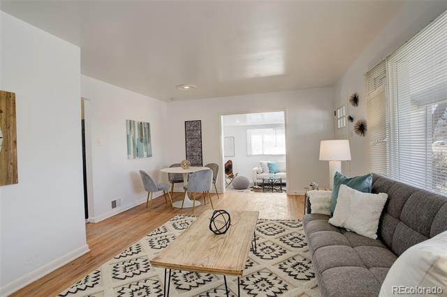 Living room with gray sofa, patterned rug, wood coffee table, and adjoining dining area.