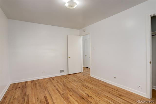 Empty room with hardwood floors, white walls, and an open doorway.