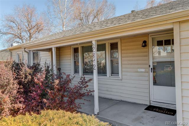 Single-story home with a covered porch, white entry door, and shrubs along the front.