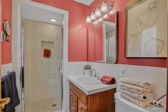 Bathroom with coral walls, a glass shower, and a wood vanity topped with folded towels.