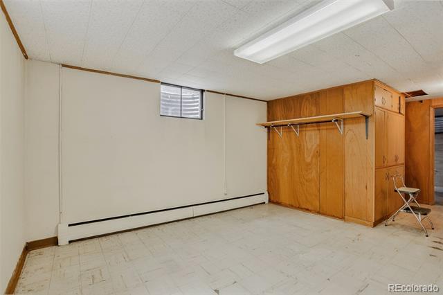Vacant room with built-in wood cabinetry, an open hanging rail, and a small high window.