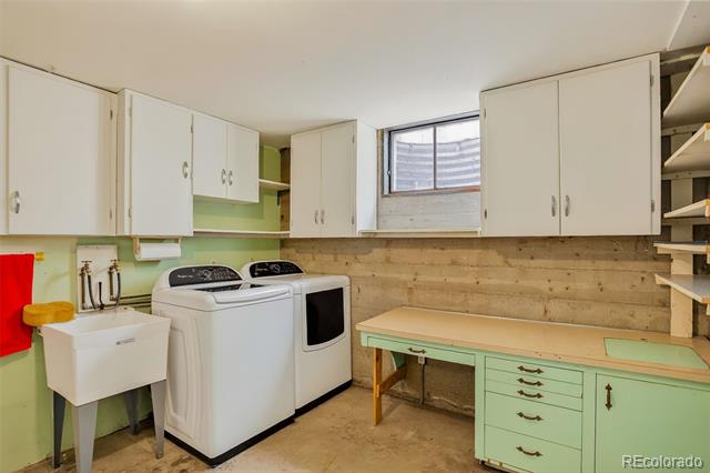 Laundry room with a white washer and dryer, utility sink, and mint-green workbench.