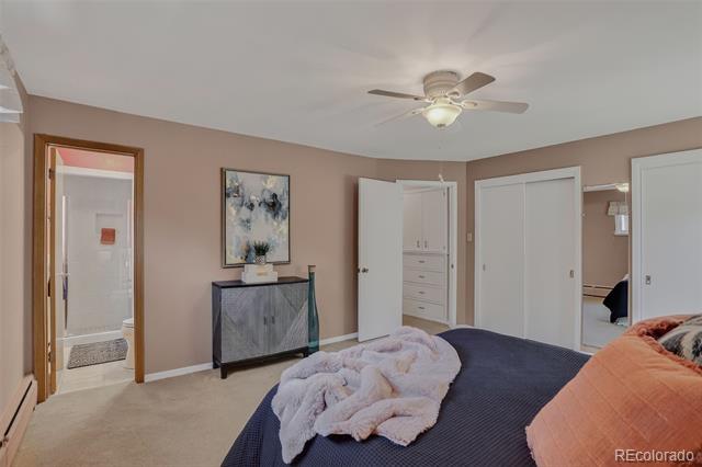 Furnished bedroom with a dark bedspread, pale pink blanket, ceiling fan, and gray dresser.