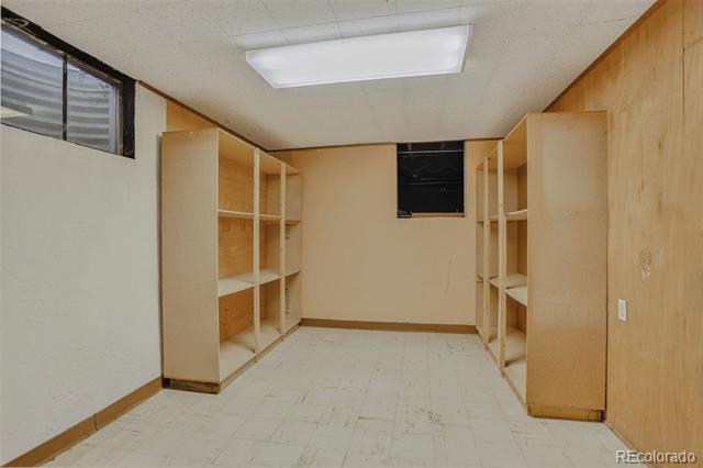 Empty storage room with built-in wooden shelving and a small high window.