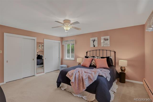 Bedroom with peach walls, a dark metal bed, pink bedding, and white closet doors.