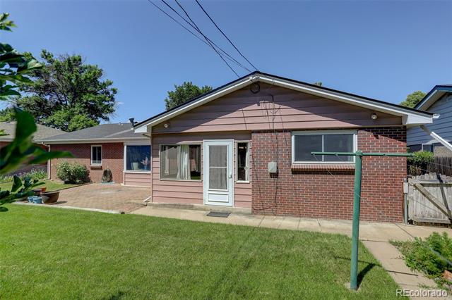 Single-story brick house with a broad green lawn, patio, and fenced backyard.