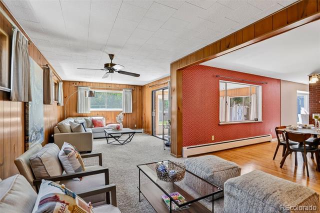Living and dining area with wood paneling, gray carpet, and a red accent wall.