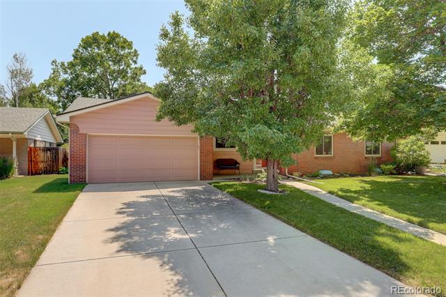 Brick house with a two-car garage, wide driveway, and large tree shading the front yard.