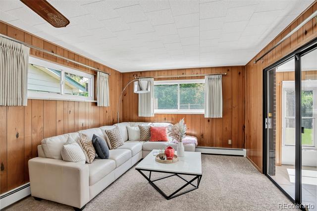 Living room with wood-paneled walls, a white sectional sofa, and sliding glass patio doors.