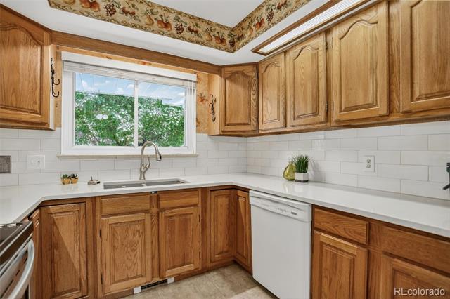 Kitchen with oak cabinets, white tile backsplash, and a sink beneath a window.