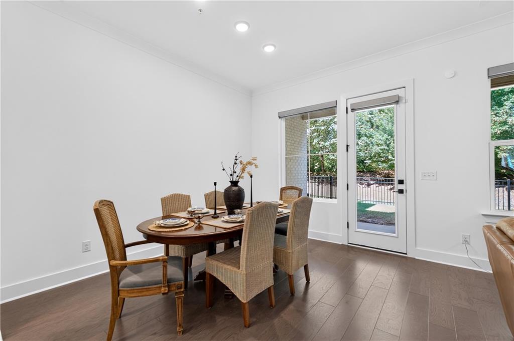 Dining area with a round table and wicker chairs beside a glass door opening to a patio.