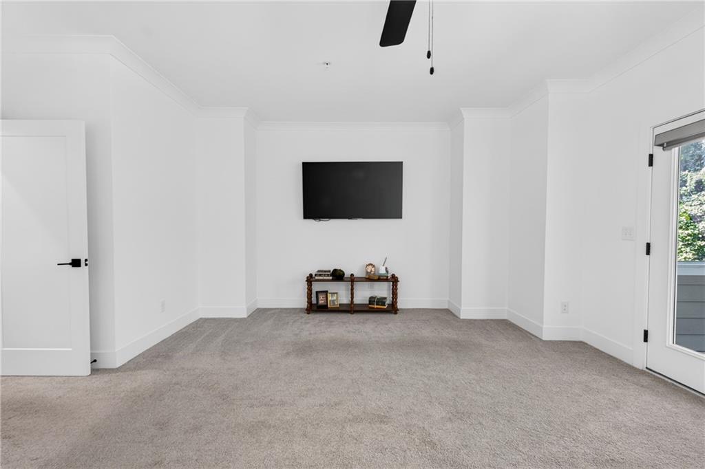 Carpeted room with a wall-mounted TV, small console, and glass exterior door.